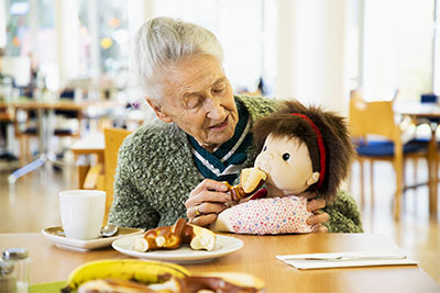 Une personne âgée donnant à manger à une poupée d'empathie Une personne âgée donnant à manger à une poupée d'empathie